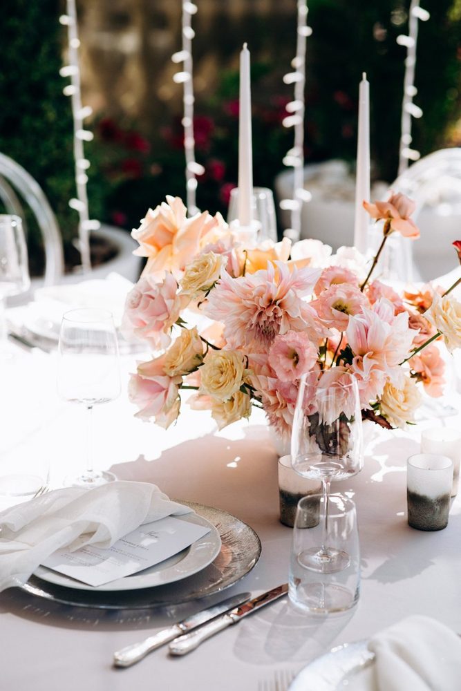 Table setting with blush and peach flowers, glassware and taper candles